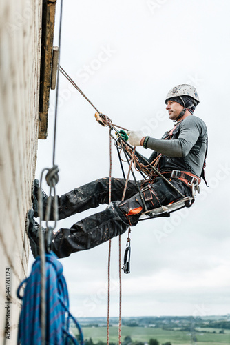 Male worker rope access industrial working at height tank oil wearing harness, helmet safety equipment rope