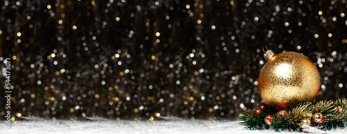 Christmas banner decorations view of gold evening ball with gold glitter on it in christmas wreath with red berries on dark background with silver and gold colors bokeh. Holidays concept copy space