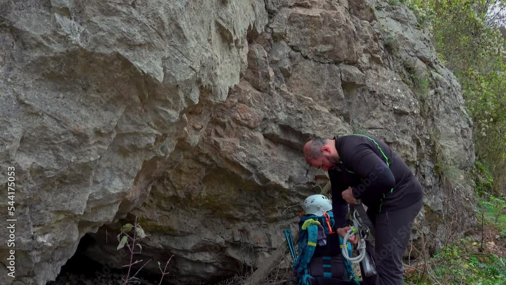 Middle age man equipping himself after climbing on a rock in a sunny autmn day - via ferrata/klettersteig
