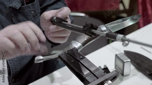 A professional sharpens a hunting knife using high-precision and efficient equipment photo