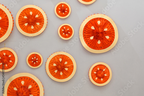 Colored paper folding circle shape in the form of an orange fruit on a gray wall