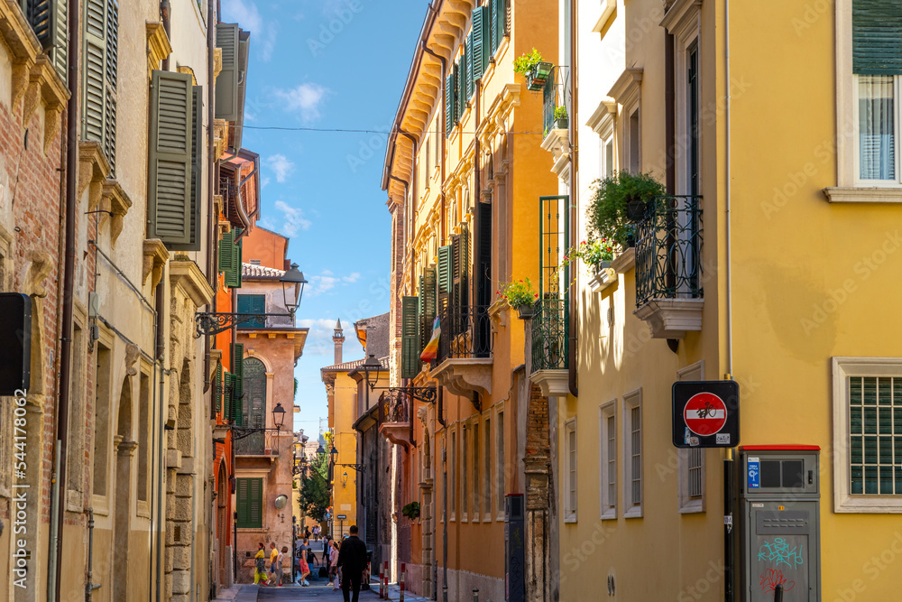 A narrow street of shops and cafes in the historic medieval old town center of Verona, Italy.	