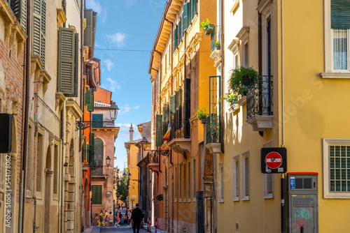 A narrow street of shops and cafes in the historic medieval old town center of Verona, Italy. 