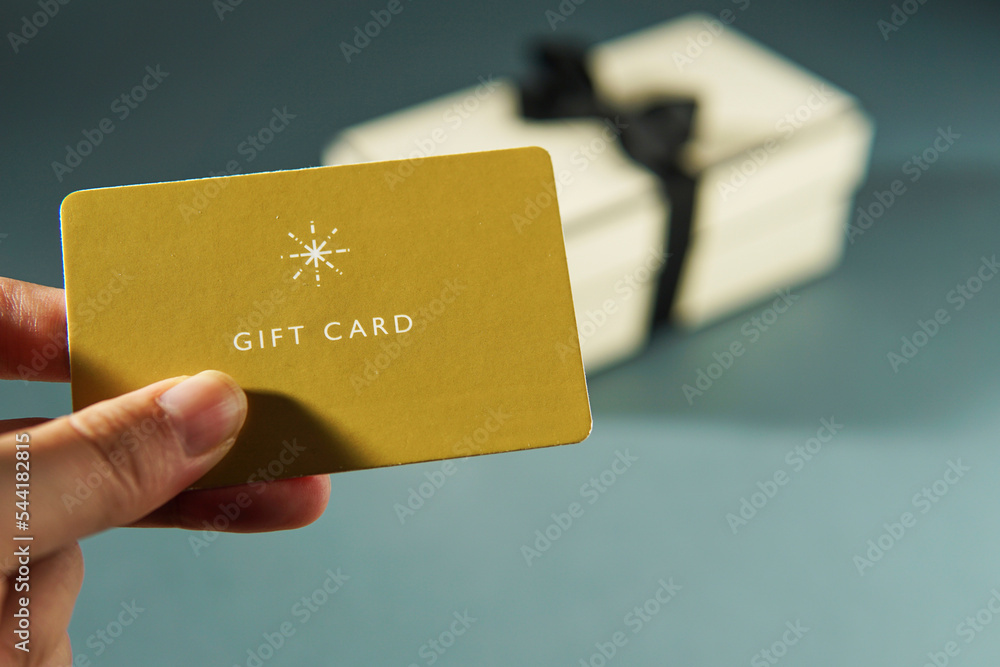 Hand holding a yellow gift card against a gift box background Stock
