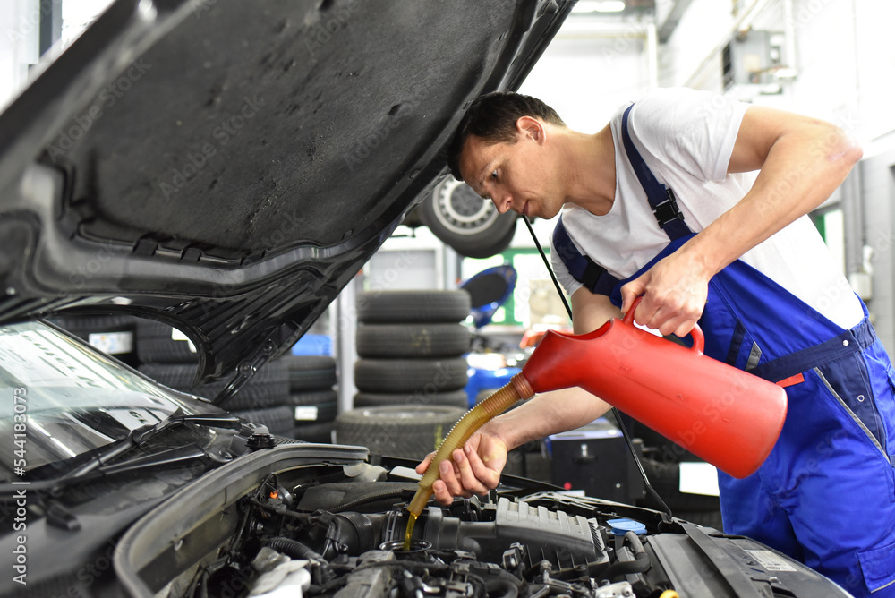 oil change from the engine of a car in a workshop by a professional mechanic - after-sales service