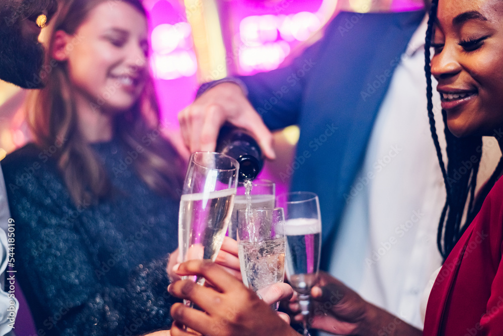 Focus on a flute glasses while pouring champagne and celebrating in the club Focus on a flute glasses while pouring champagne and celebrating in the club