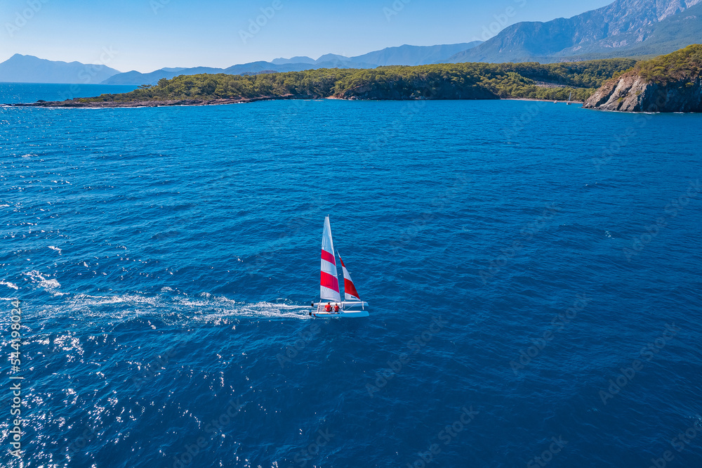 Fototapeta premium Aerial view beautiful white yacht wirh sail on clear blue sea in Turkey. Concept sport travel by drone
