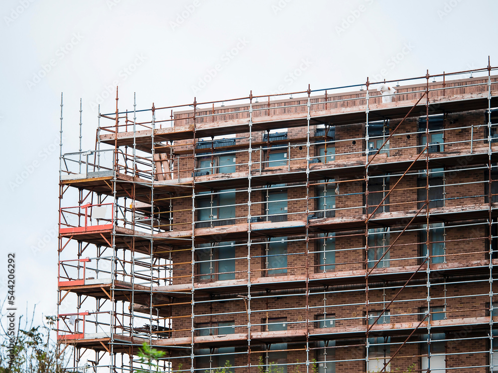 Construction site with modern building in scaffolding. Brick house, residential or commercial property development.