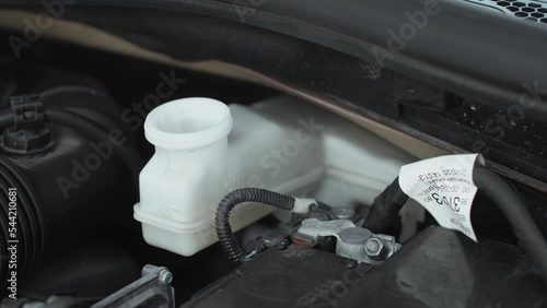 a man checks the brake fluid dot4 in the car before driving. unscrews by hand and tightens the black cap of the white tank