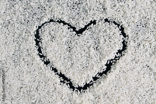 Heart-shaped rice on dark background. Love and valentines day concept. Raw long white rice in shape of heart. Traditional Asian food.