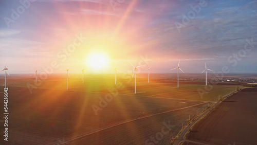 Wind turbines in the sunset standing in the field from the drone point of view