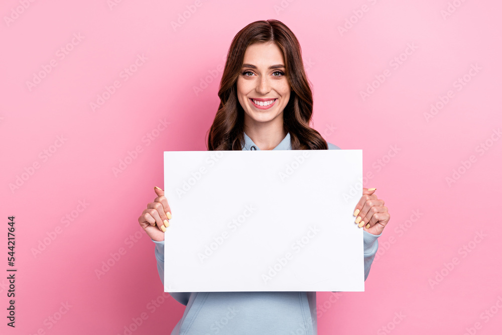 Photo of positive nice girl arms hold demonstrate empty space paper blank isolated on pink color background Photo of positive nice girl arms hold demonstrate empty space paper blank isolated on pink color background