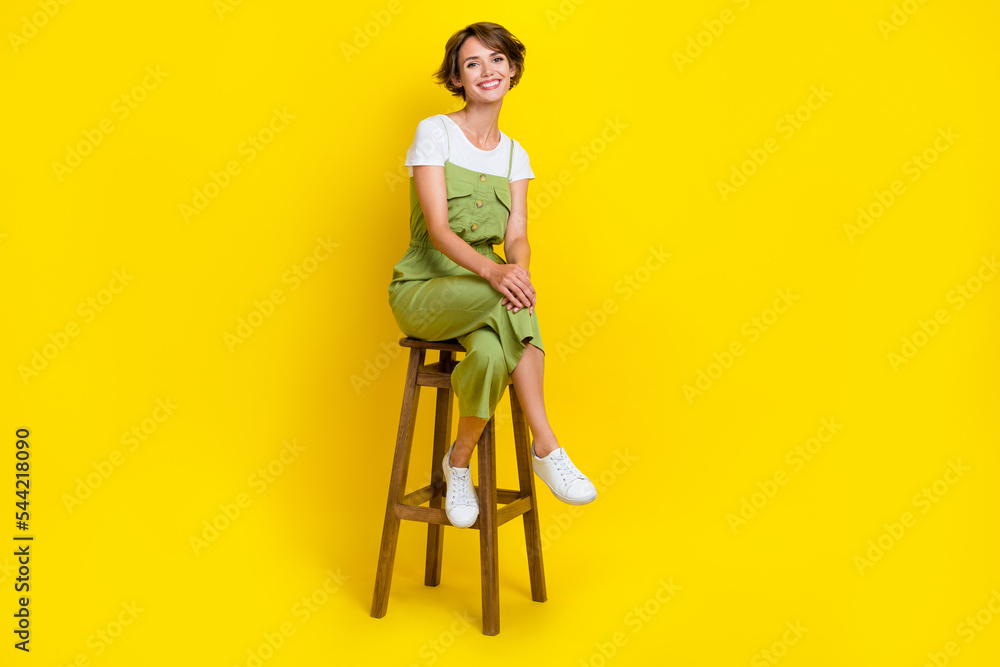 Full body length photo of adorable businesswoman sitting bar chair relax after hard working days weekend isolated on yellow color background