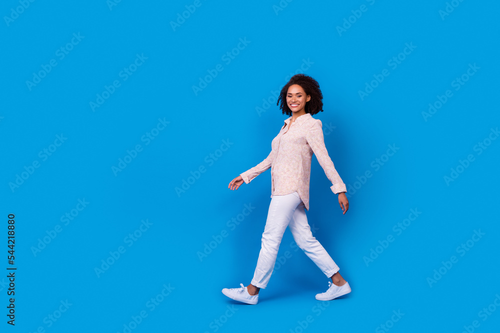 Obraz premium Full body profile portrait of charming pretty lady walking empty space isolated on blue color background
