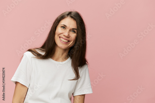 horizontal portrait of a cute attractive woman on a pink background in a clean white tank top smiling pleasantly at the camera © Tatiana