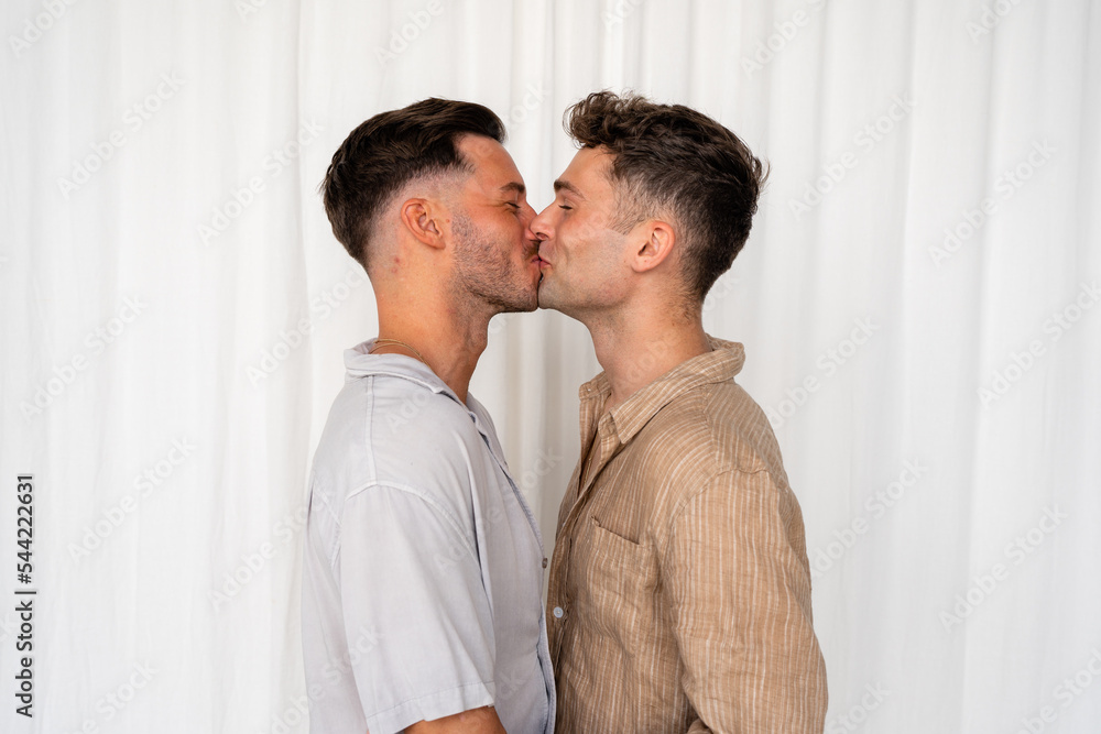 Beautiful Gay couple kissing and laughing with white curtain background Beautiful Gay couple kissing and laughing with white curtain background