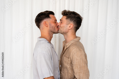 Beautiful Gay couple kissing and laughing with white curtain background