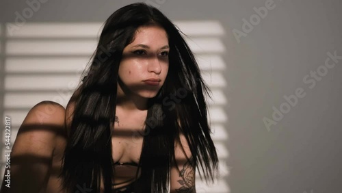 Portrait of young Native American woman in a dark studio light falls on her through the blinds. photo