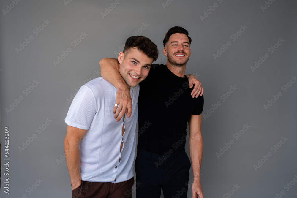 beautiful gay couple smiling and arms around shoulders looking at camera beautiful gay couple smiling and arms around shoulders looking at camera
