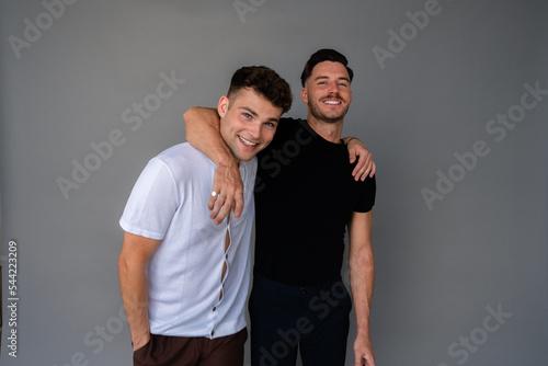 Fototapeta beautiful gay couple smiling and arms around shoulders looking at camera