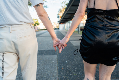 lesbian couple loosely holding hands on pathway photo