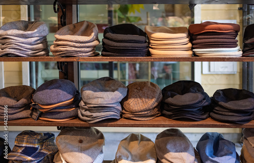 Varieties of caps and hats for men on the shelf of a clothing shop. Peaky blinders style hats. 1920s years style. photo