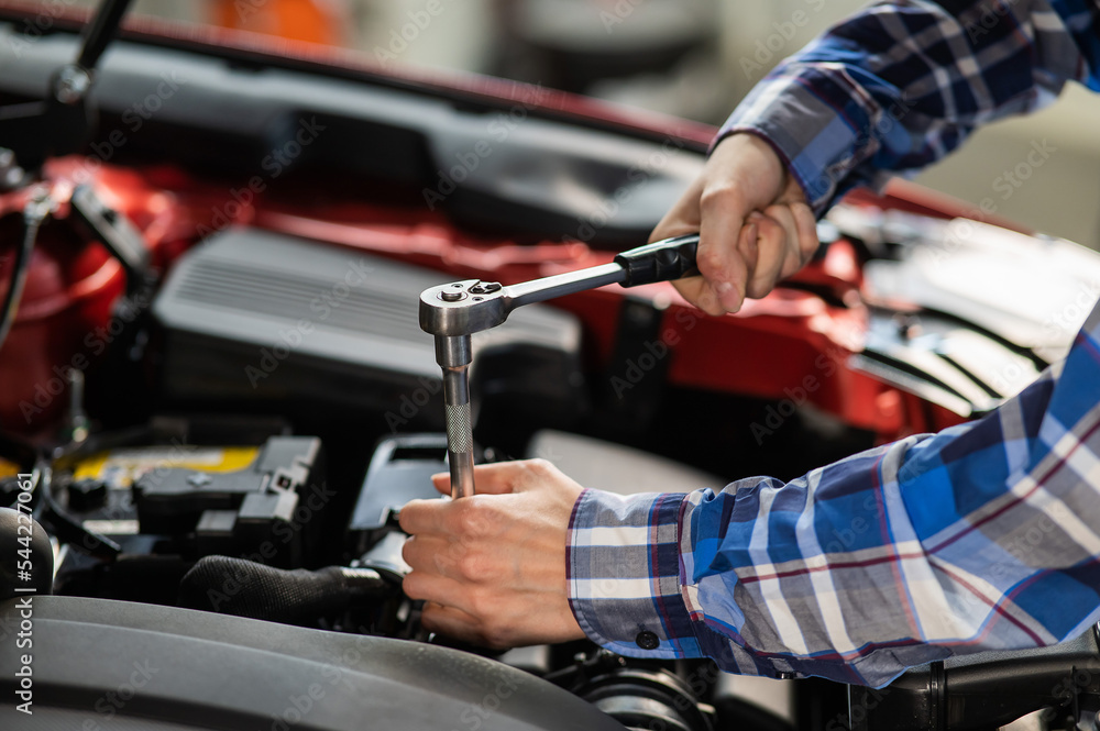 Female auto mechanic unscrewing a nut to replace a car spark plug. Female auto mechanic unscrewing a nut to replace a car spark plug.