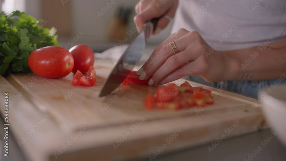 Close up of Hands cutting tomatoes on cutting board in kitchen Close up of Hands cutting tomatoes on cutting board in kitchen