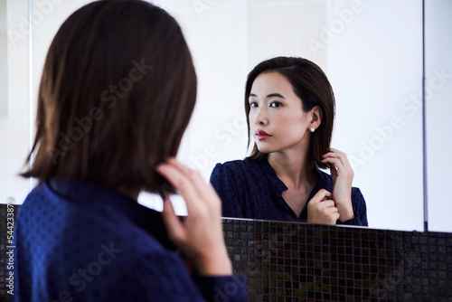 鏡の前でピアスをつける30代女性 photo