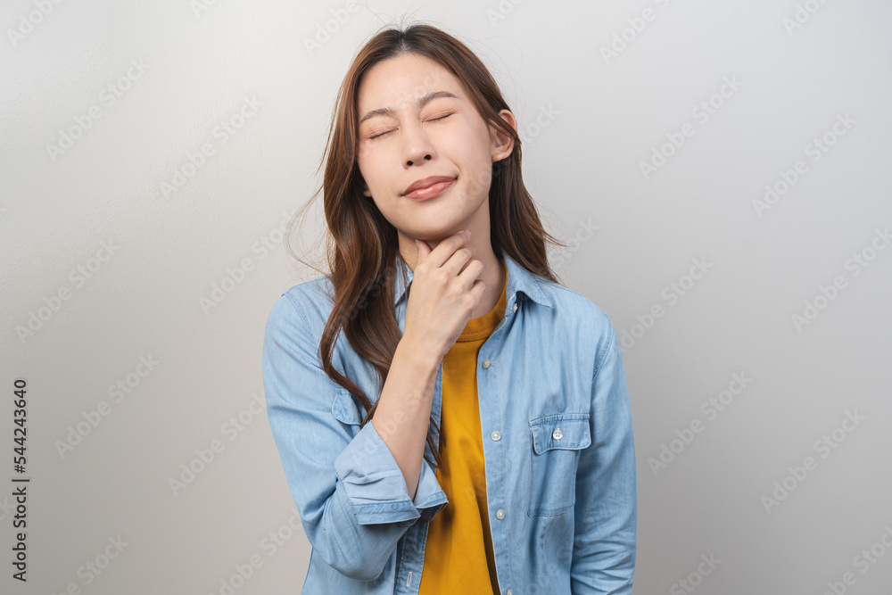 Sickness in inflaming asian young woman, girl use hand check self touch at sore throat, pain thyroid gland on neck or disease reflux, acid of suffer people on wall background. Medical and healthcare. Sickness in inflaming asian young woman, girl use hand check self touch at sore throat, pain thyroid gland on neck or disease reflux, acid of suffer people on wall background. Medical and healthcare.