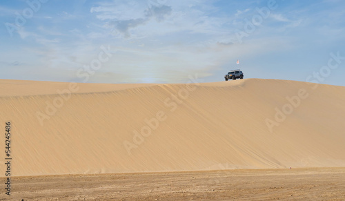 Sealine,Qatar- october 10,2022 : a vehicle at the top of the sealine dunes. photo