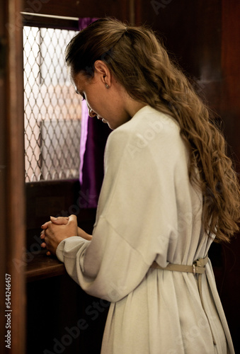 Christian woman, church and confessional, worship and prayer for forgiveness, mercy and peace to holy God, praying and faith. Spiritual person in booth, sorry about sin, secret and trust to priest photo