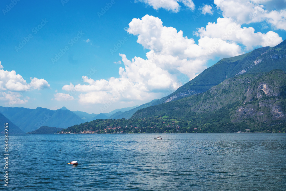 Beautiful panoramic view of the speed boat cruising along Lake Lugano, with the green Swiss Alps in the background on a sunny summer day. Canton of Ticino, Switzerland.