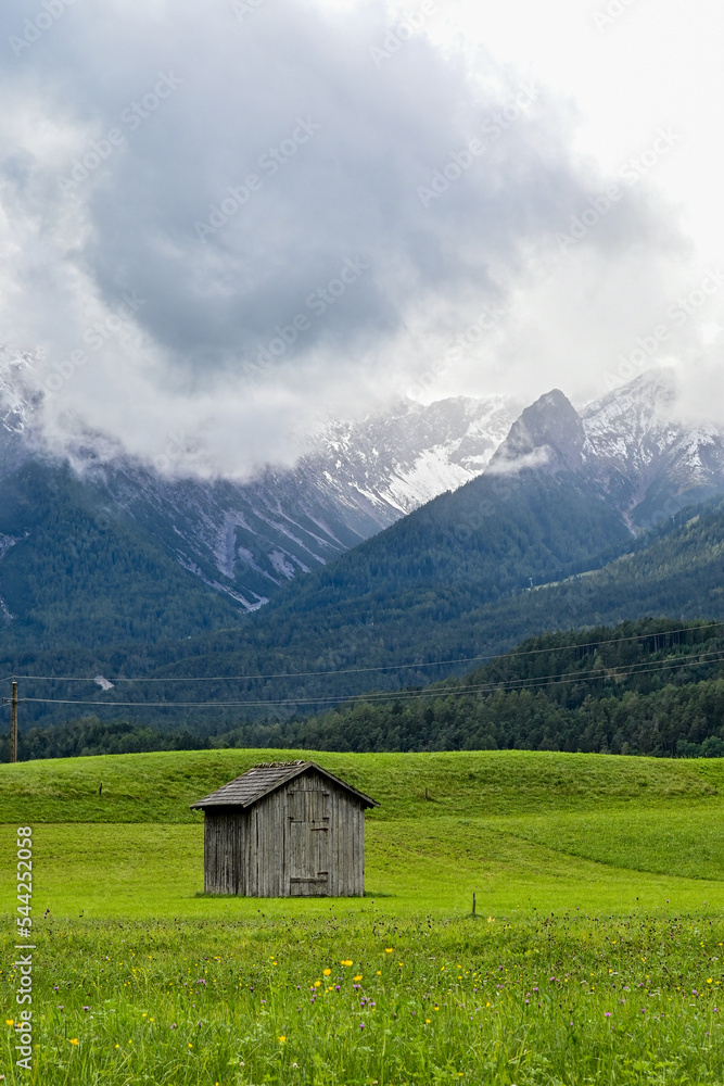 Alter Heustadl auf einer Wiese im Tal bei Imst, mit Blick auf die umliegende Berge Muttekopf, Tirol, Österreich