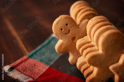 Homemade smiling gingerbread man cookie peeking out from a row of cookies. Standing out from crowd concept photo