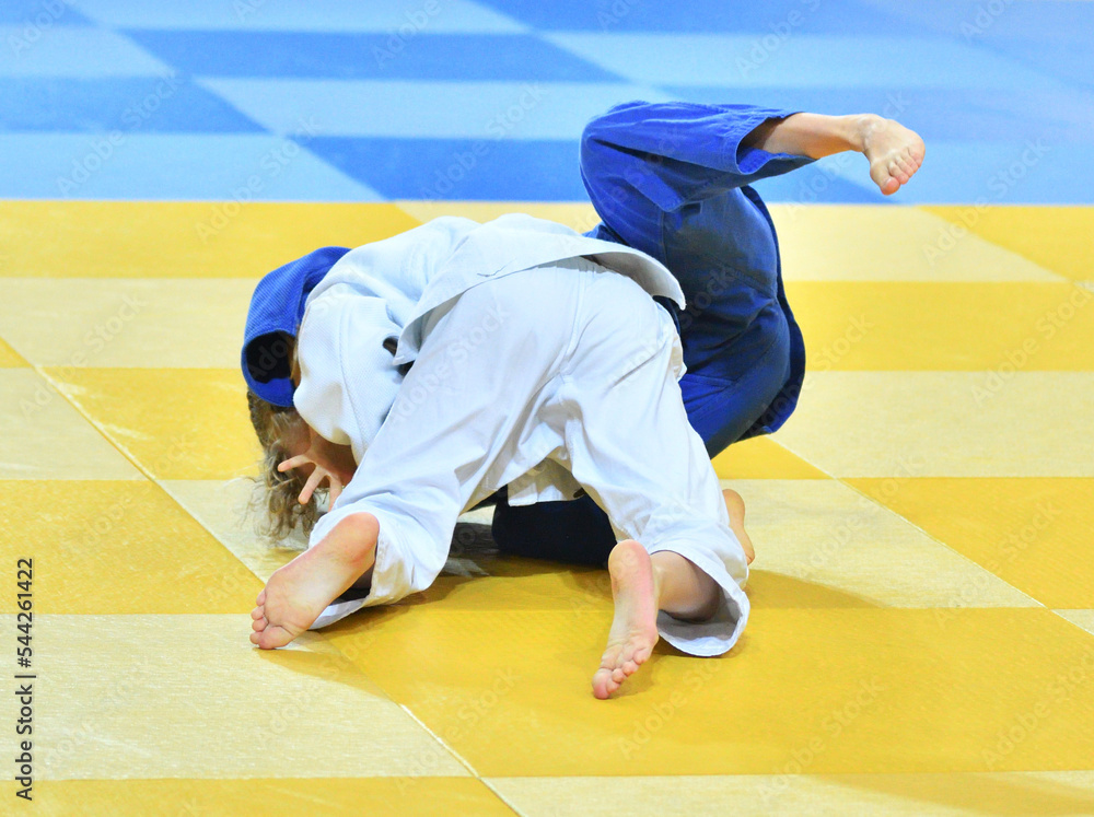 Fighter girls in judogi compete in judo on the tatami