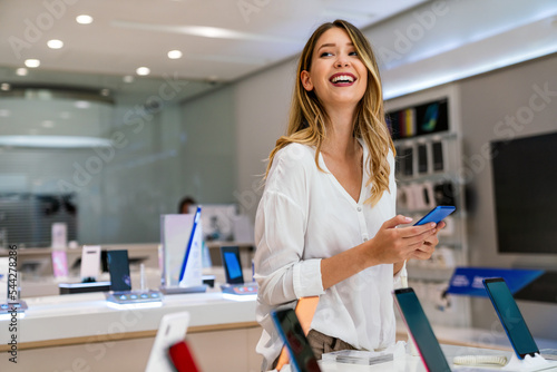 Canvas Print Portrait of happy young woman buying a new smartphone in store