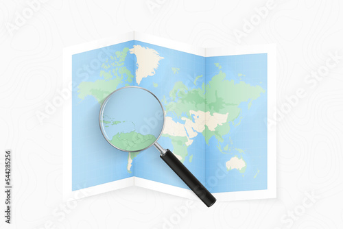 Enlarge Antigua and Barbuda with a magnifying glass on a folded map of the world.
