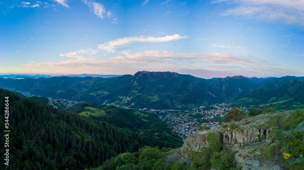 Fototapeta premium Bulgarian town Smolyan with lake, vegetation and clouds. Rhodope Mountains. Panorama, top view