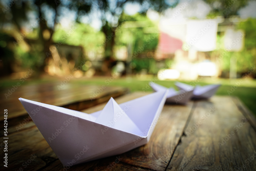 Origami, white paper boat isolated on a wooden floor.  Paper boats mean walking.  feeling of freedom  leadership