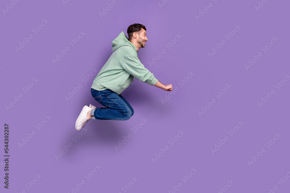Full size photo of handsome young guy jumping pushing invisible shopping cart wear trendy gray outfit isolated on violet color background