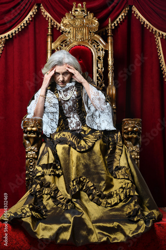 senior queen in a dress sits on a throne