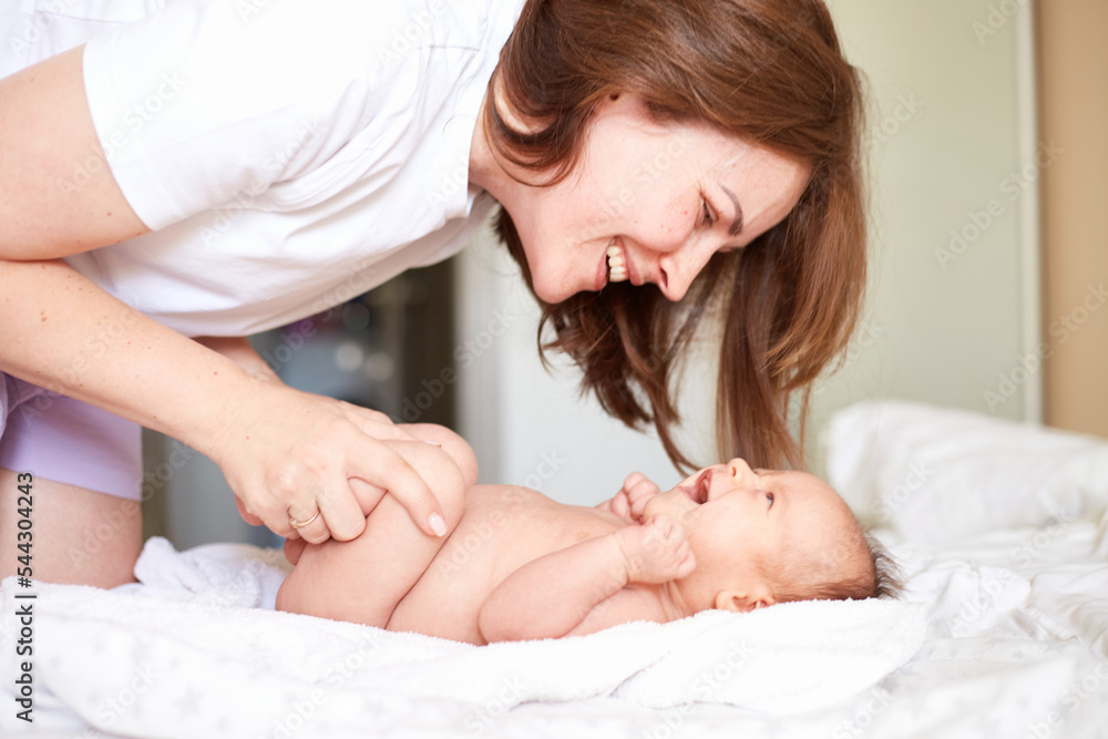 Mother Massaging Her newborn baby boy. Realistic home portrait Mother Massaging Her newborn baby boy. Realistic home portrait
