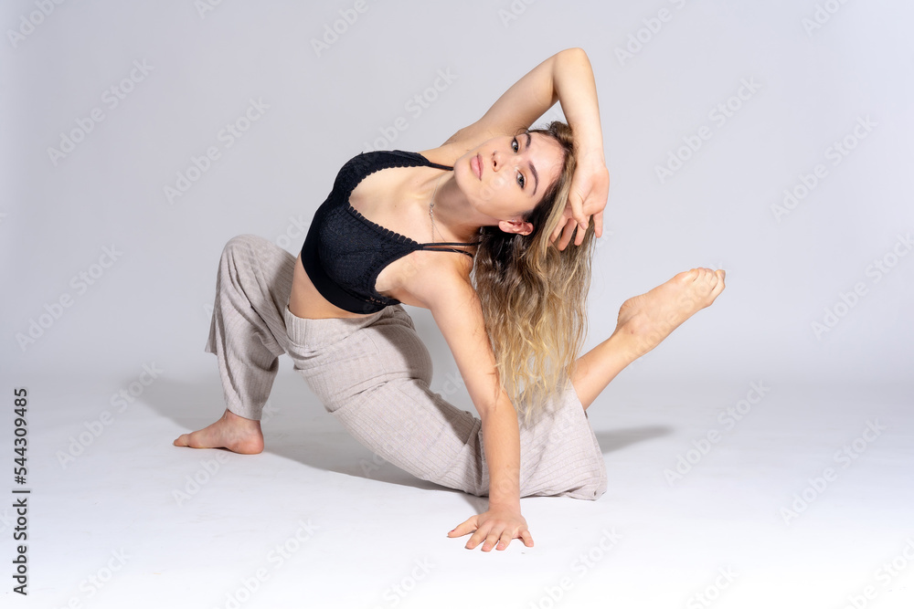 Young dancer in studio photo session with a white background, ballet, performing exercises on the floor