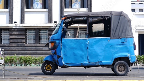 Jakarta three wheeler know as bemo or bajai is parked on the side of the road photo