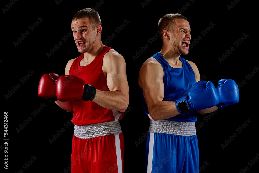 Winner emotions. Two twins brothers, professional boxers in blue and red sportswear isolated on dark background. Concept of sport, competition, training, energy.