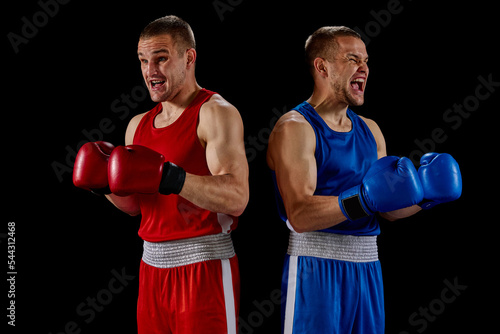 Winner emotions. Two twins brothers, professional boxers in blue and red sportswear isolated on dark background. Concept of sport, competition, training, energy. © master1305