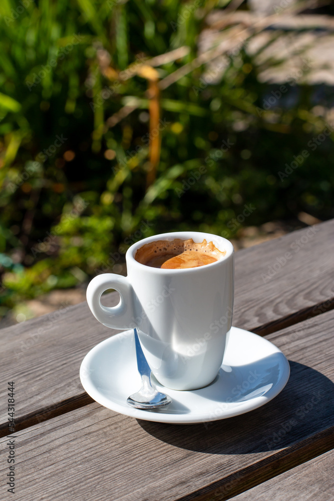 A cup of coffee on a table against the backdrop of nature in the garden