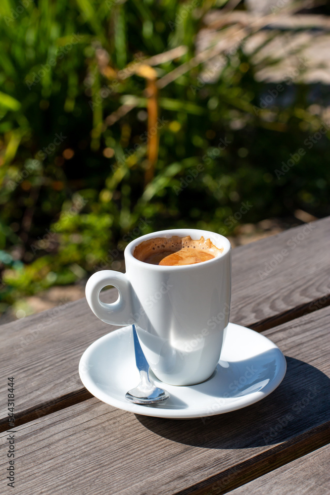 A cup of coffee on a table against the backdrop of nature in the garden A cup of coffee on a table against the backdrop of nature in the garden
