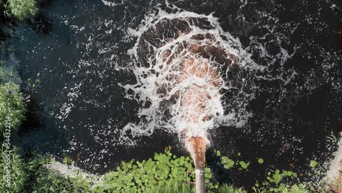 Dirty water pours out of the pipe into the river. Environmental pollution.